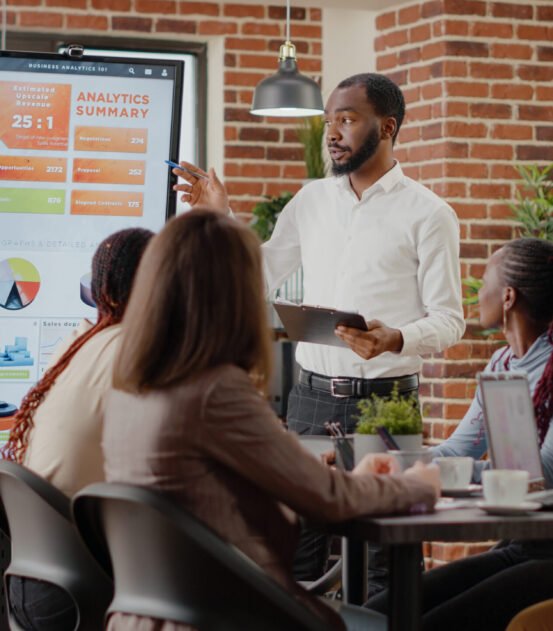 Company employee presenting business strategy with charts on monitor, planning project. Workmates analyzing financial statistics on display, working together on company development.