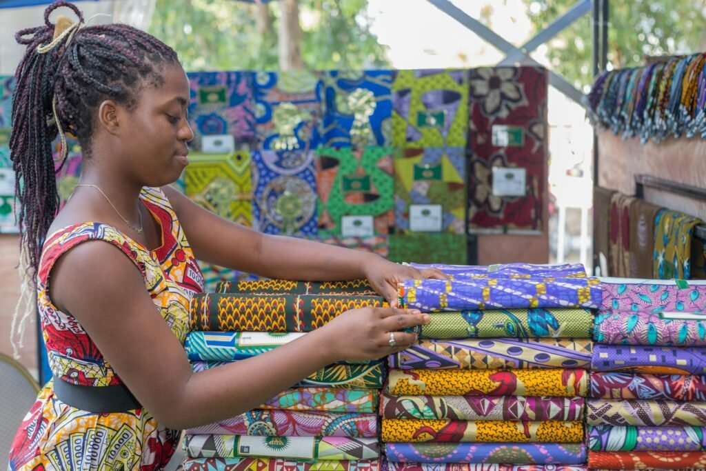 A young entrepreneur arranging colourful fabrics at her stall