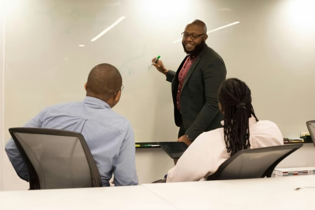 A trainer presenting at a whiteboard to a group of professionals